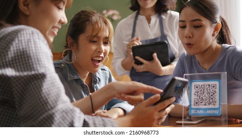 Adult waiter staff casual apron SME owner enjoy work listen to young asia people smile fun talk look at smart QR code on mobile app eat vegan meal after reopen coffee shop food drink inside cafe bar. - Powered by Shutterstock