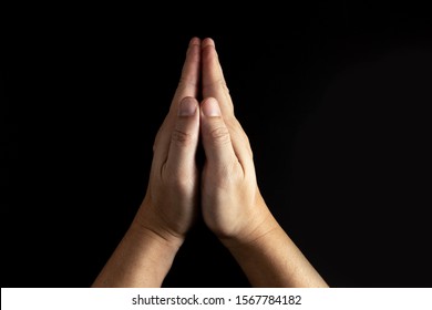An adult whose hand is prayed on the black or dark background.Respect for belief in religion and God. top-down, flat lay, top view. peace concept. Power of hope or love and devotion. - Shutterstock ID 1567784182