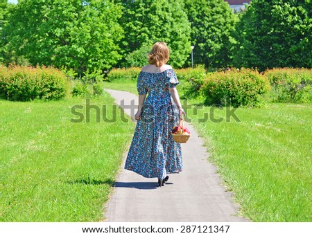 An adult woman with a basket of fruit in the park
