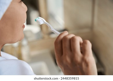 Adult woman brushing her teeth in bathroom - Powered by Shutterstock