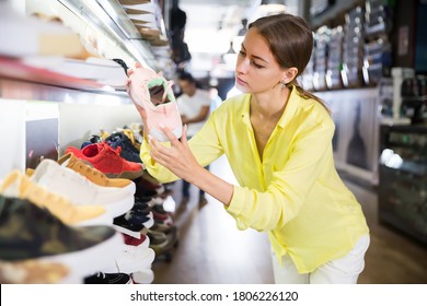 Adult Woman Choosing Sneakers In Streetwear Store