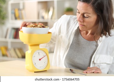 Adult Woman Dieting Measuring Food With Scale Weighting Cereal Bowl At Home