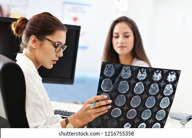Adult woman discussing x-ray results during visit at female doctor's office
