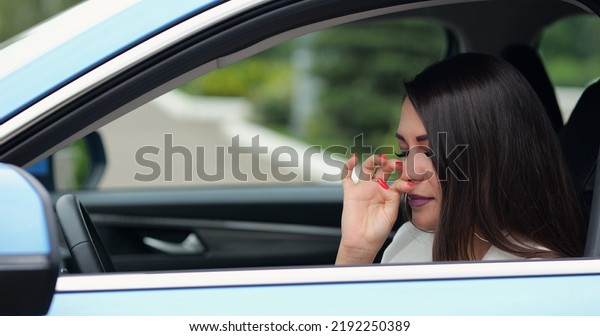 Adult woman driver feels sick sneezing in\
car. Businesswoman touches face with napkin and makes sure about\
appearance sitting in black leather\
cabin