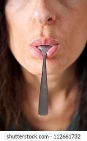 Adult Woman Face With A Metal Spoon In Her Mouth