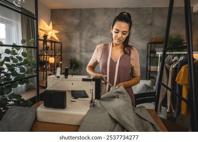 Adult woman fashion designer or tailor hold scissors cut textile on the table at home or studio - Powered by Shutterstock