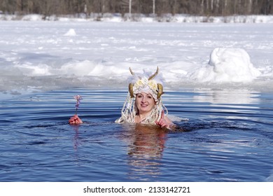 An Adult Woman In A Faun Costume Is Bathing In Cold Water In An Ice Hole On Sunny Winter Day.