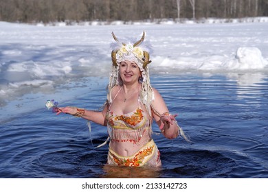 An Adult Woman In A Faun Costume Is Bathing In Cold Water In An Ice Hole On Sunny Winter Day.