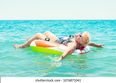 Adult Woman Floating In A Rubber Ring In The Sea.