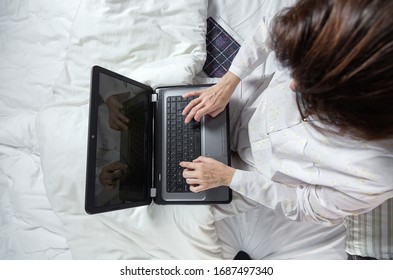 Adult Woman With Glasses, Working At Home Working At Home In Her Pijama With A Laptop And A Mobile Phone. Work From Home Concept