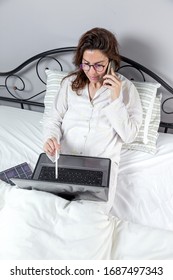 Adult Woman With Glasses, Working At Home Working At Home In Her Pijama With A Laptop And A Mobile Phone. Work From Home Concept