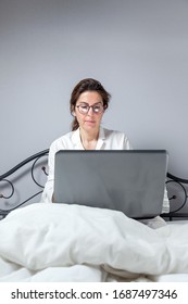 Adult Woman With Glasses, Working At Home Working At Home In Her Pijama With A Laptop And A Mobile Phone. Work From Home Concept