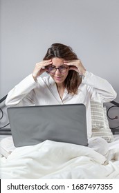 Adult Woman With Glasses, Working At Home Working At Home In Her Pijama With A Laptop And A Mobile Phone. Work From Home Concept