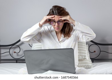 Adult Woman With Glasses, Working At Home Working At Home In Her Pijama With A Laptop And A Mobile Phone. Work From Home Concept