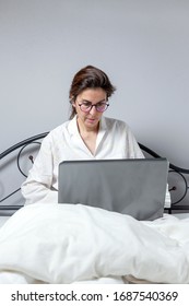 Adult Woman With Glasses, Working At Home Working At Home In Her Pijama With A Laptop And A Mobile Phone. Work From Home Concept