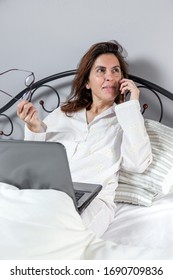 Adult Woman With Glasses, Working At Home Working At Home In Her Pijama With A Laptop And A Mobile Phone. Work From Home Concept