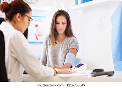 Adult woman having blood pressure test during visit at female doctor's office