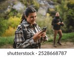 Adult woman hiker look for path and directions on mobile phone