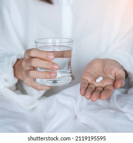 Adult Woman Holding Pill And Glass Of Water, Female Taking Medicine On Bed At Home. Migraine, Painkiller, Headache, Influenza, Illness, Sickness And Healthcare Concept