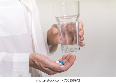 Adult woman holding pills and glass of water. Age, medicine, healthcare concept. Selective focus.  - Shutterstock ID 758158942