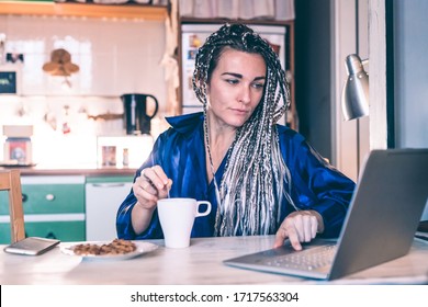 Adult woman indoor at home kitchen having breakfast using computer - searching news, streaming, video call concept