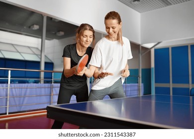 Adult woman instructor teaching female student play table tennis - Powered by Shutterstock