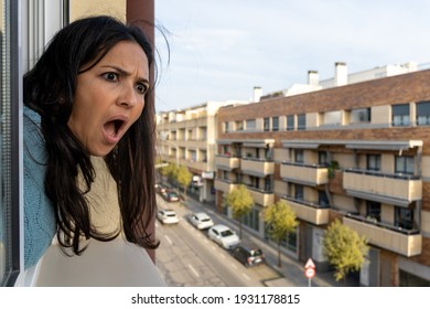 Adult Woman Looking Out The Window At Home And Putting Surprise Face.