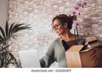 Adult Woman Lost His Job And Move Her Stuffs From The Desk. Adult Female People With Box And Personal Things Inside In Front Of Laptop Computer And Work Place. Office Lifestyle And Career Business