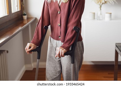 Adult Woman On Crutches At Home. Fracture Of The Leg Or Foot. Concept Of Rehabilitation And Healing. Orthopedics And Traumatology. Unrecognized Person