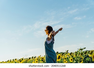 Adult Woman With Open Arms In A Field Of Sunflowers. Feeling Of Freedom