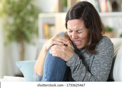 Adult Woman In Pain Suffering Knee Ache Sitting On A Couch At Home