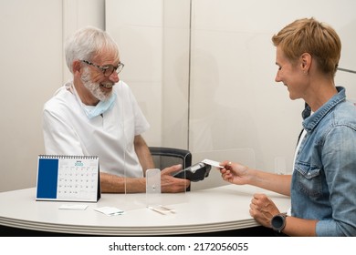 Adult Woman Paying For Visit In Dentist Office In The Medical Clinic With Card.