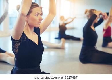 Adult Woman Performing Ballet And Sitting With Hands Up In Class And Stretching.