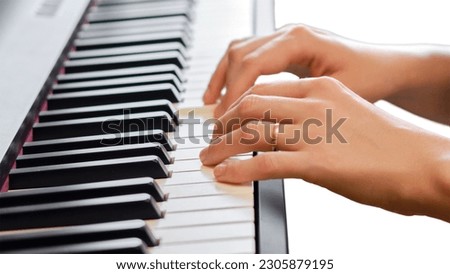 An adult woman plays an electric piano, hands close-up, isolated on white background. Female hands on the keys of a portable electronic piano