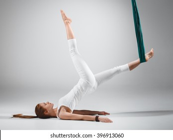 An adult woman practices different inversion - anti-gravity yoga positions in a bright well lit studio. 