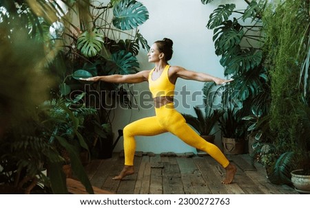Adult woman practices yoga among the urban jungle. Female in yoga asanas and Pilates at home. Lifestyle concept.