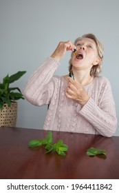 An Adult Woman Puts Drops Of CBD Cannabis Oil Into Her Mouth. Alternative Medicine.