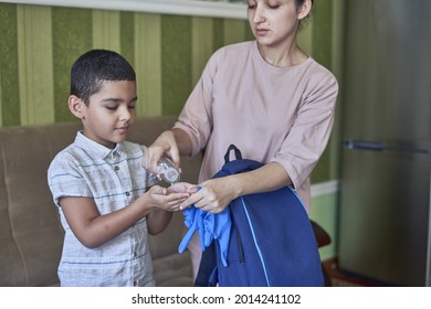 An Adult Woman Putting Hand Sanitizer On A Young Pupil's Hands Before Going To School