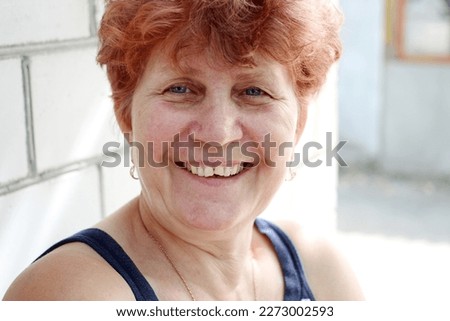 Adult woman with short red hair smiling at camera