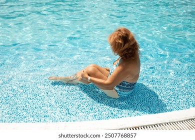 Adult woman sitting in bikini swimsuit in blue water pool. Healthy lifestyle in retirement. Back view - Powered by Shutterstock