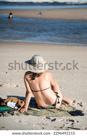 Adult woman, sitting on the sand of Taquari on Guaibim beach, late afternoon, in Valenca, Bahia.