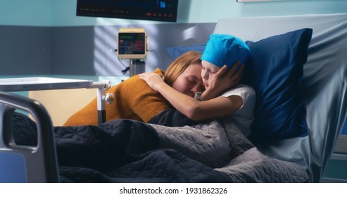 Adult Woman Speaking And Embracing Boy With Cancer While Visiting Patient In Ward Of Oncology Clinic