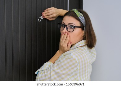 Adult Woman Standing Near The Front Door And Looking Through The Peephole. Emotion Fear, Surprise, Fright