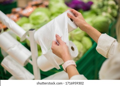 Adult Woman Taking One Plastic Package From The Roll Of Packing Plastic Bags In The Vegetable Department Of The Supermarket Or Grocery Store