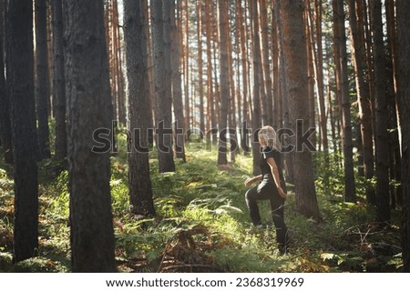An adult woman walks through pine forest in rays of the morning sun, forest bathing, relaxation idea