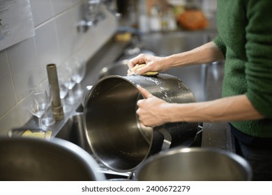 Adult Woman Washes Cooking Pots by Hand in a Restaurant Kitchen Close Up Side View - Powered by Shutterstock