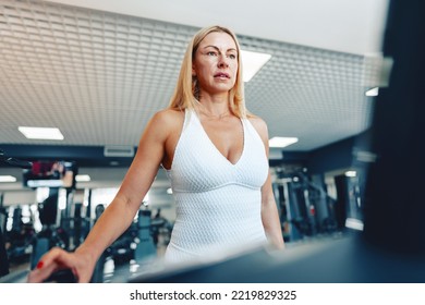 Adult Woman In White Tracksuit Running On A Treadmill In A Gym