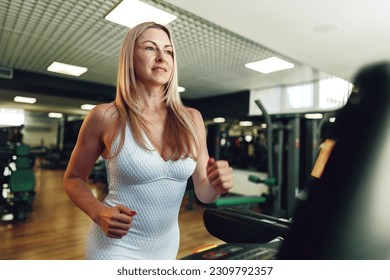Adult woman in white tracksuit running on a treadmill in a gym