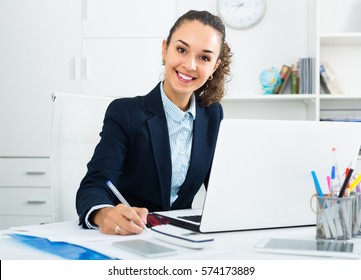 Adult woman working with paperwork and laptop in office