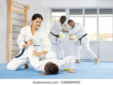 Adult woman and young female judoka practicing judo technique in group in gym - Powered by Shutterstock